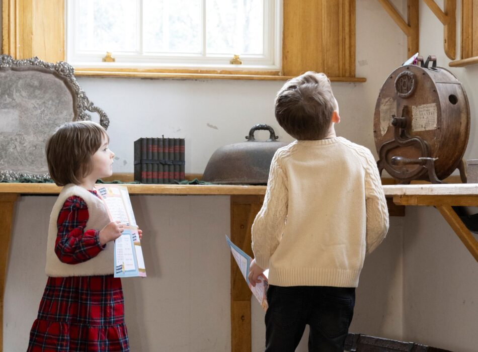 Two children holding activity sheets while exploring historic objects at Ardgillan Castle