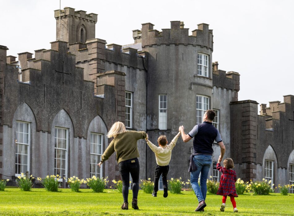 Parents and children running together on the grass in front of Ardgillan Castle enjoying a family day out