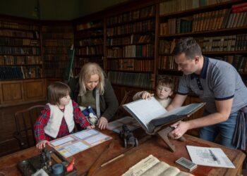 A family of four gathered in the study of Ardgillan Castle reading books
