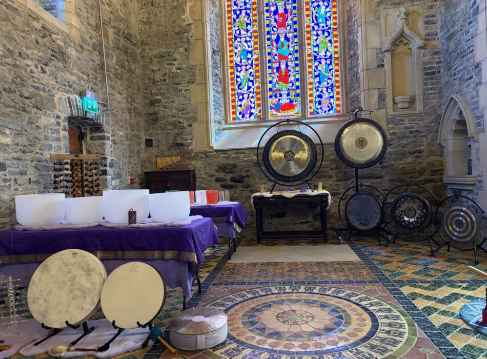A wide view of a sound bath set up with a stained glass window in the background.