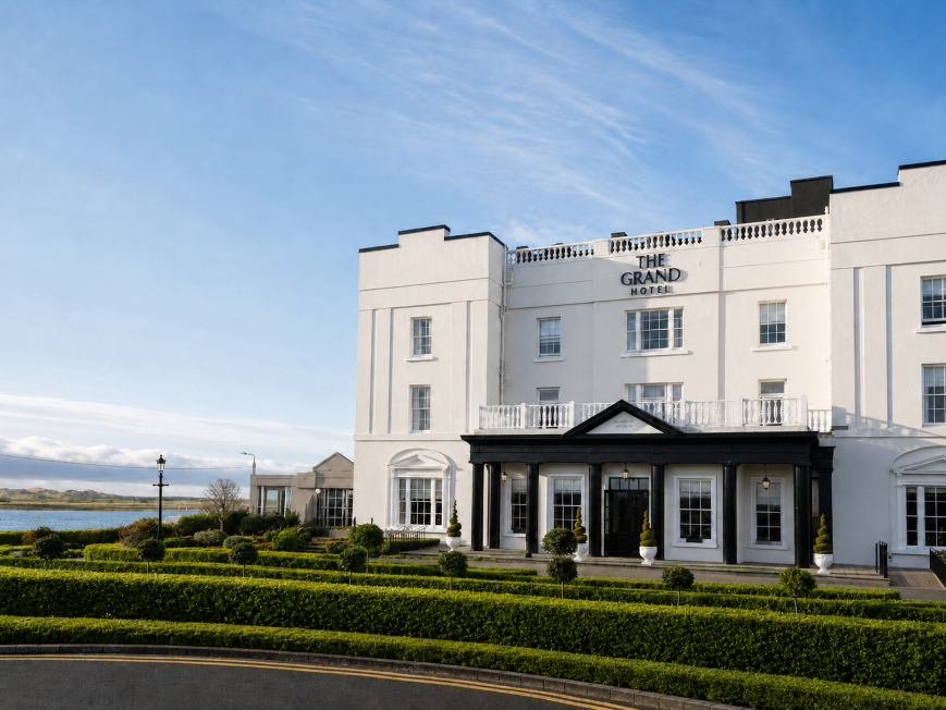 Elegant penthouse bedroom with floor-to-ceiling windows offering panoramic views across the coastline and surrounding landscape.